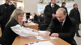 Vladimir Poutine signe la liste d'émargement dans un bureau de vote de Moscou. Le parti Russie unie du Premier ministre et candidat à la présidentielle sortirait large vainqueur des élections législatives de dimanche, selon la télévision d'Etat, tout en e