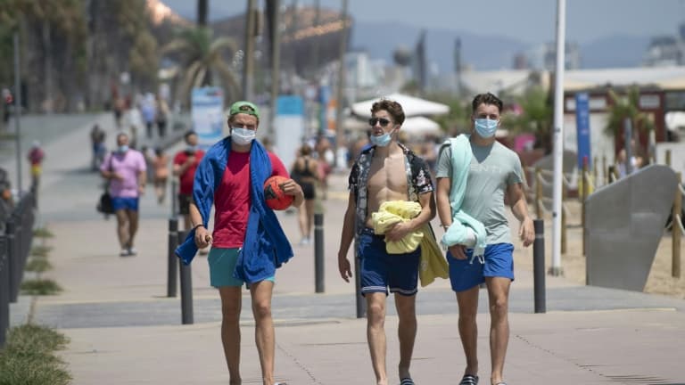 Des promeneurs avec les masques le long de la plage à Barcelone, le 18 juillet 2020