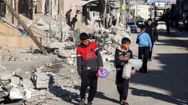 Des enfants partent collecter de l'eau dans la ville de Rafah détruite, le 14 février 2024 