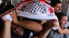 Des Palestiniens portent, ce samedi, le corps d'un adolescent tué par balle dans le camp de réfugiés de Jalazoun.