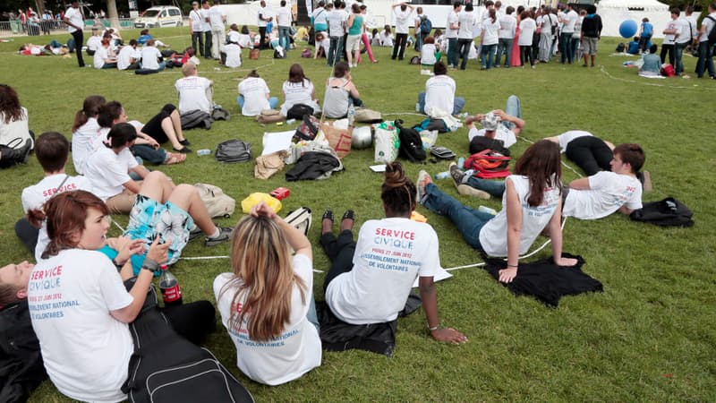 Des jeunes engagés dans le service civique discutent, assis sur la pelouse du Champs-de-Mars, à Paris le 27 juin 2012