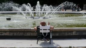 Un homme prend le soleil près d'une fontaine du jardin du Palais Royal, lors d'un pic de chaleur, le 31 juillet 2020 à Paris