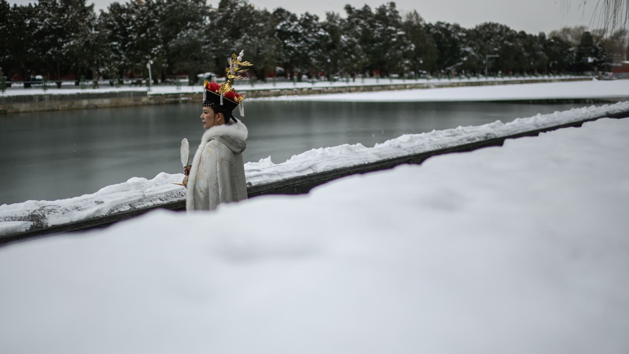 Une femme portant un costume traditionnel pose à la Cité interdite un jour après une chute de neige à Pékin le 21 février 2024.
