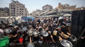Des Palestiniens portant des casseroles pour recevoir des repas chauds, dans la ville de Gaza, le 23 juillet 2025.