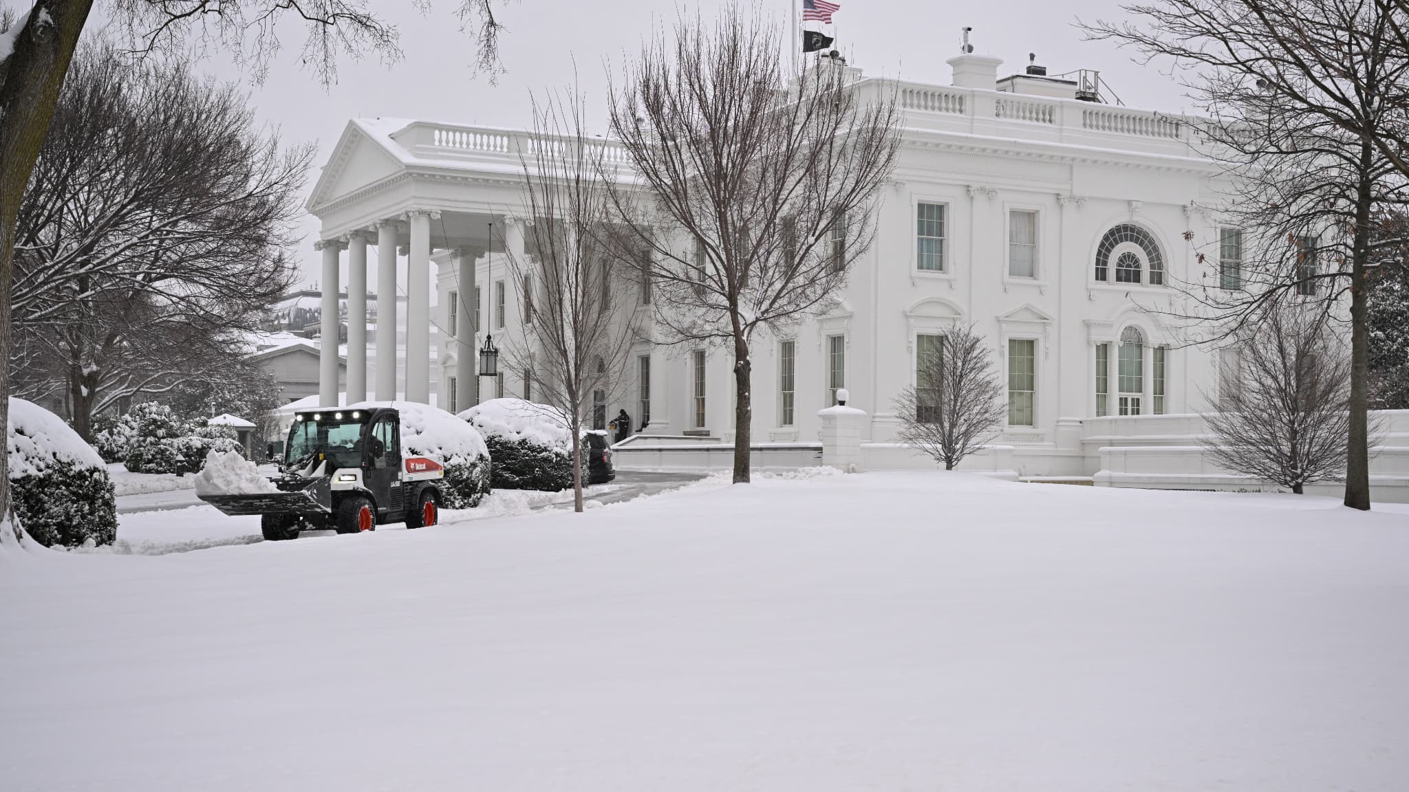 Des travailleurs déneigent un trottoir à la Maison Blanche à Washington, DC, le 6 janvier 2025.