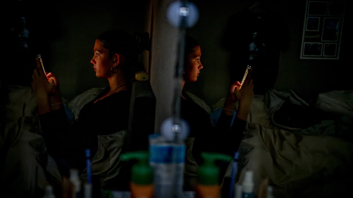 Une adolescente concentrée sur son smartphone dans sa chambre. (Photo d'illustratrion)