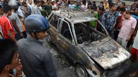Des passants népalais regardent les restes calcinés d'un taxi brûlé lors des heurts entre manifestants et forces de l'ordre