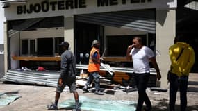 Des employés ramassent des débris près d'une bijouterie dégradée et pillée après une quatrième nuit consécutive d'émeutes, le 1er juillet 2023 à Marseille
