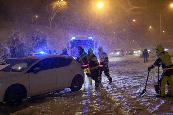 Des pompiers poussant un véhicule enneigé à Madrid, le 8 janvier 2021