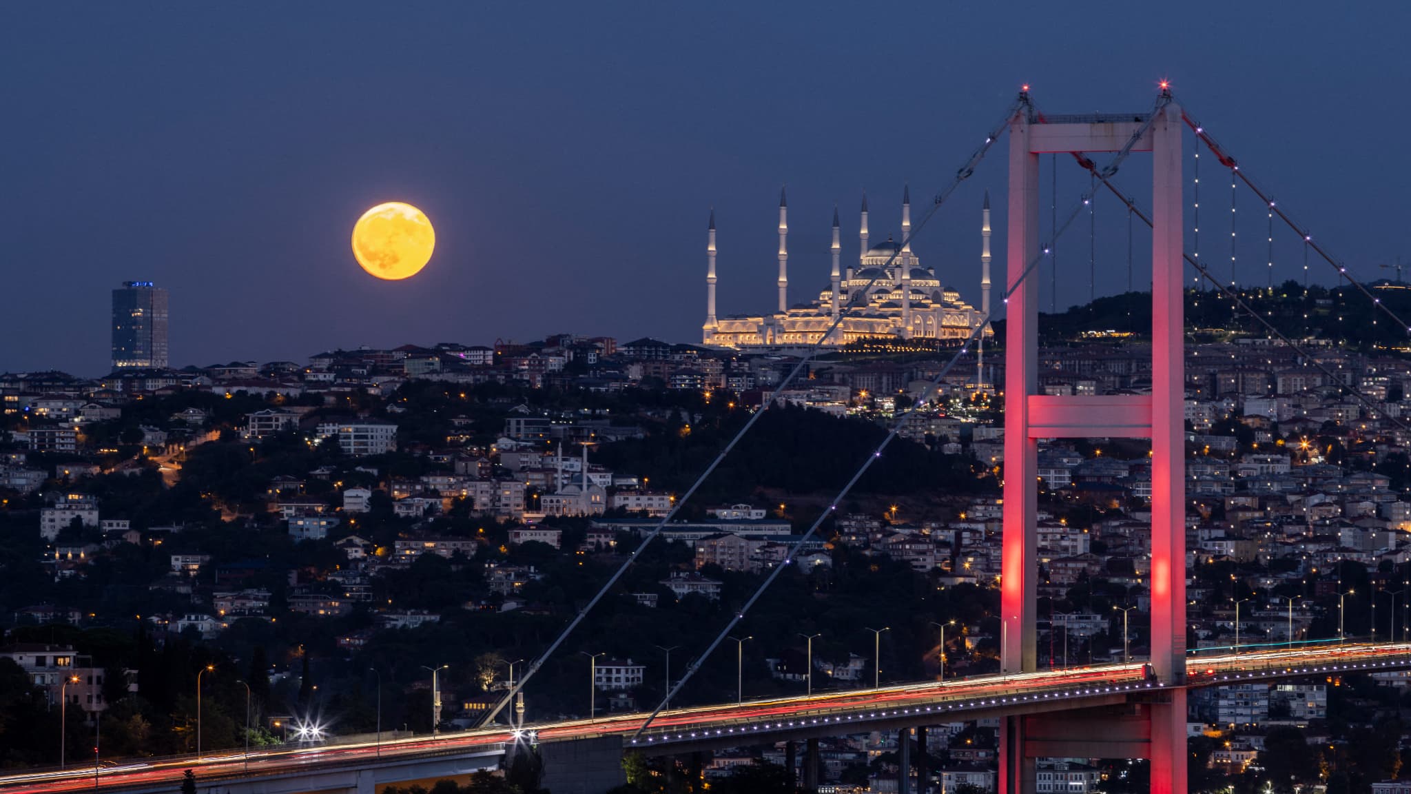 Une super lune bleue se lève derrière le pont des martyrs du 15 juillet et la mosquée Camlıca à Istanbul, le 19 août 2024.