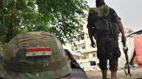 Un soldat syrien posté près d'un casque orné d'un drapeau syrien, à Homs, le 27 mai 2014.