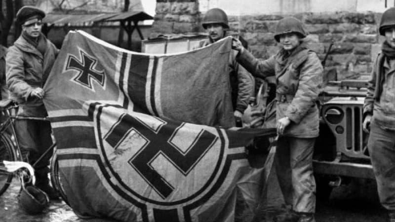 Des soldats anglais tenant un drapeau nazi au moment de la libération (photo d'illustration)