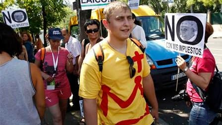 Au premier jour des 26es Journées mondiales de la Jeunesse à Madrid, des pèlerins (au centre) passent devant des manifestants protestant contre les réductions de tarif accordées aux pèlerins étrangers dans les transports publics de la ville. En période de