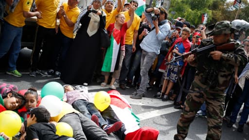 Un homme pointe une arme semblant être réelle vers des enfants, lors de la manifestation pro-Gaza à Paris, le 9 août 2014.