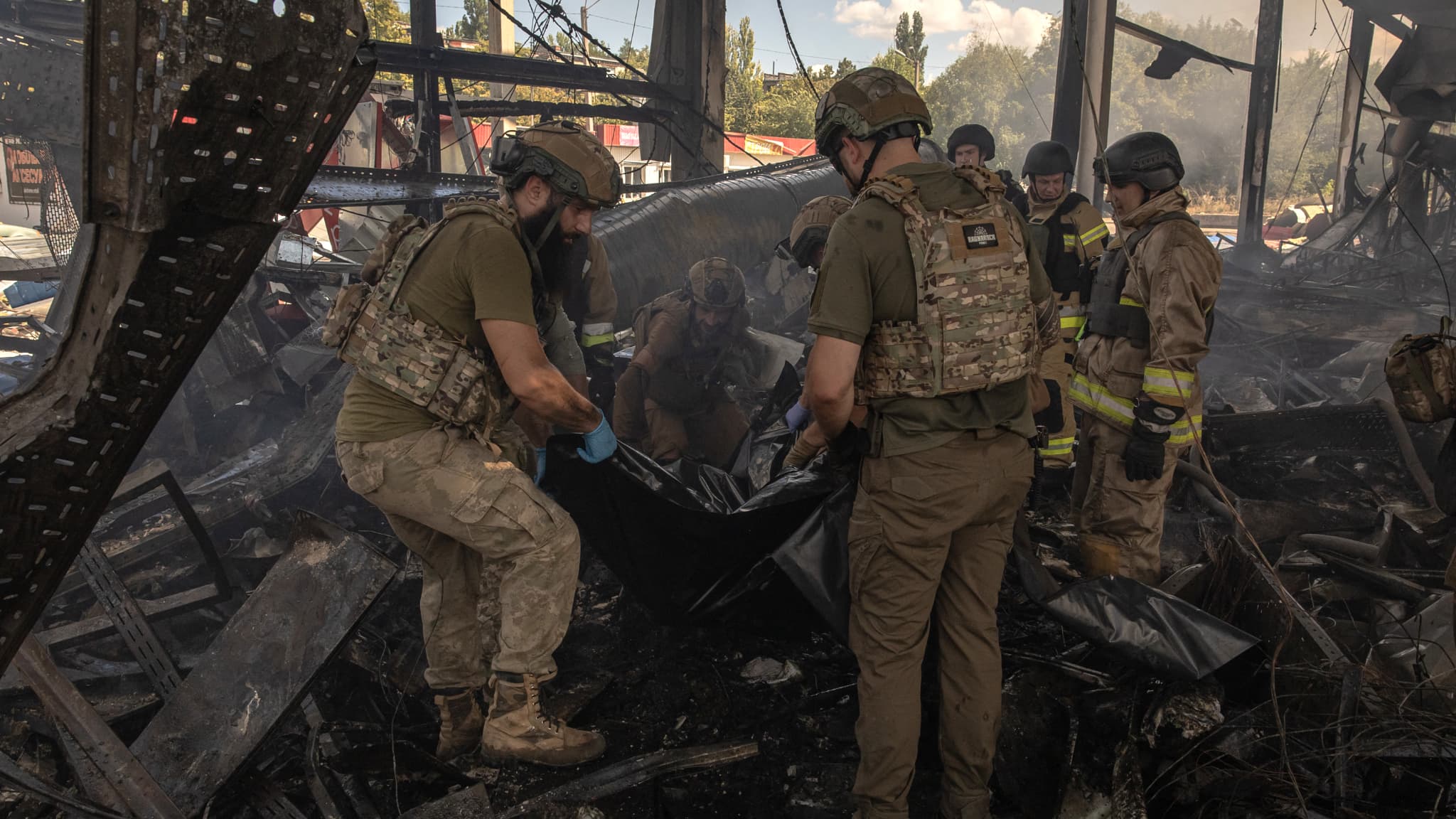 Des secouristes et des militaires ukrainiens récupèrent le corps d'une victime dans les décombres du supermarché détruit à la suite d'une attaque russe, à Kostyantynivka, dans l'est de la région de Donetsk, le 9 août 2024