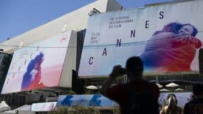 Un piéton prend une photo des affiches de la 78e édition du Festival de Cannes devant le Palais des Festivals à Cannes, dans le sud de la France, le 12 mai 2025