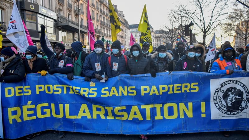 Des manifestants tiennent une banderole sur laquelle est écrit "Postiers sans papiers, régularisation !" lors d'une manifestation en faveur de la régularisation des migrants en situation irrégulière à Paris, le 18 décembre 2021.