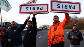 Des agriculteurs portent des panneaux d'entrée retournés de la ville de Paris, le 31 janvier 2024 près de Chilly-Mazarin en Essonne