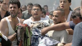 Des Libanais portent le cadavre d’une victime après une puissante explosion, à Tripoli, dans le nord du Liban,  le 23 aout 2013.
