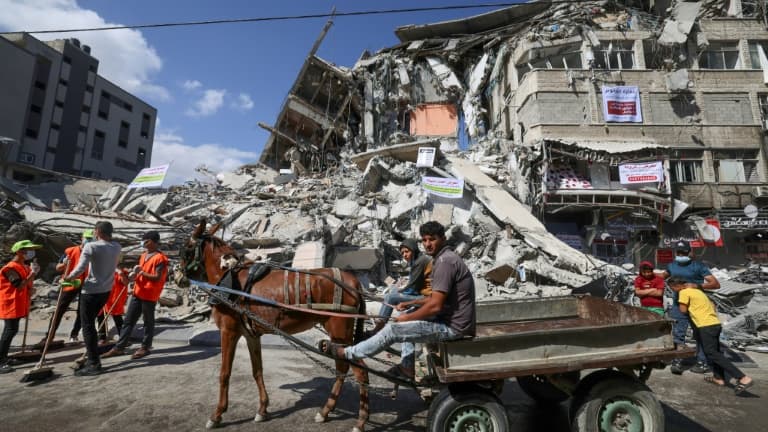 Des Palestiniens utilisent une charette pour transporter les gravats dans une rue de Gaza, le 23 mai 2021 