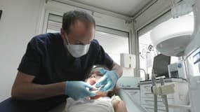 Un dentiste contrôle la dentition d'une petite-fille. 