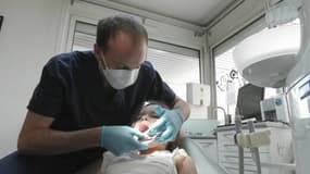 Un dentiste contrôle la dentition d'une petite-fille.