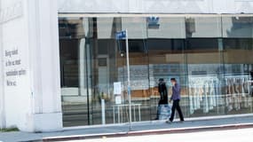 Une personne portant un masque passe devant un magasin fermé sur l'avenue Melrose à Los Angeles, le 3 août 2020
