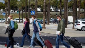 Des touristes sortent de l'aéroport à leur arrivée à Palma de Majorque le 26 mars 2021