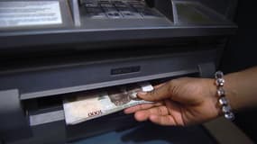 Un client retire des nairas nigérians d'un distributeur automatique de billets (DAB) dans une banque à Asaba, dans l'État du Delta, au Nigeria, le 10 novembre 2016.