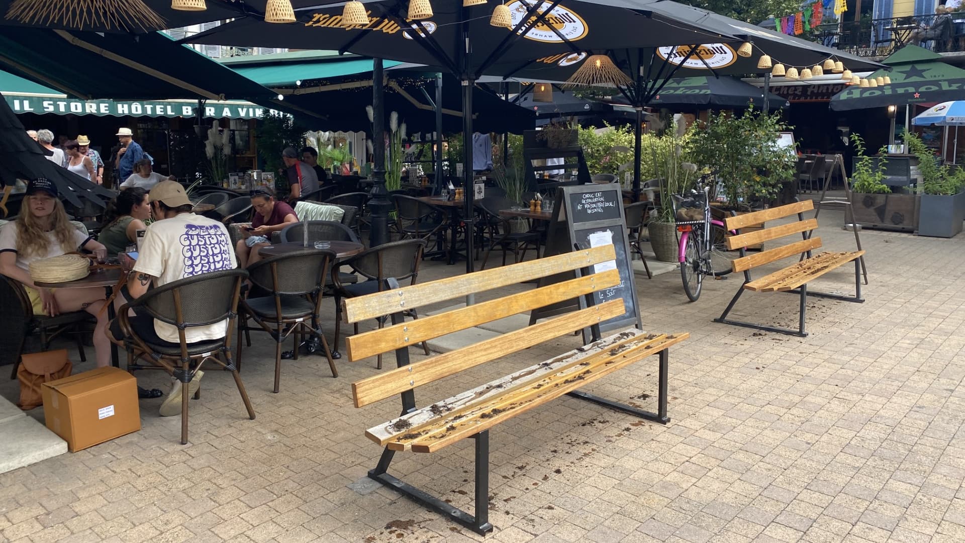 Deux bancs dégradés par du sirop et du marc de café devant le bar "Le Choucas" situé place Manuel à Barcelonnette (Alpes-de-Haute-Provence), en juillet 2023.