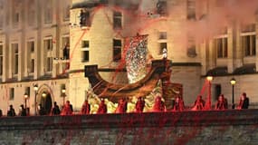 Les membres du groupe de metal Gojira perchés sur des scènes installées sur une façade de La Conciergerie, à Paris, lors de la cérémonie d'ouverture des JO de Paris le 26 juillet 2024., alors que la chanteuse lyrique Marina Viotti passe sur un décord de bateau.