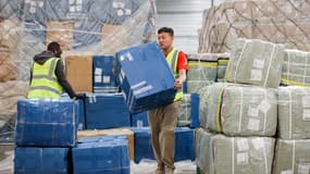 Des employés d'une société de logistique transportent des colis de fret aérien dans un entrepôt de l'aéroport Roissy-Charles de Gaulle, au nord de Paris, le 29 avril 2025