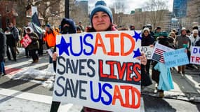 Une femme tient une pancarte soutenant l'USAID alors que des manifestants se rassemblent contre le président américain Donald Trump et ses politiques lors d'une manifestation près du Massachusetts Statehouse lors du Presidents' Day, le 17 février 2025, à Boston, Massachusetts.
