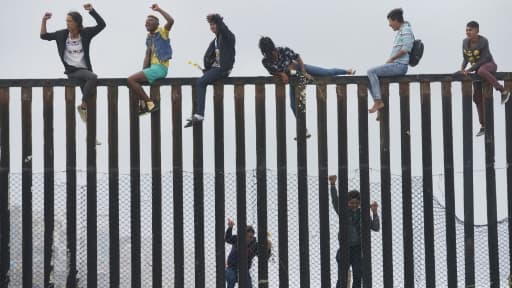Des migrants qui ont participé à la caravane des migrants escaladent la barrière entre la frontière mexicaine et les Etats-Unis, le 29 avril 2018 à San Ysidro, en Californie