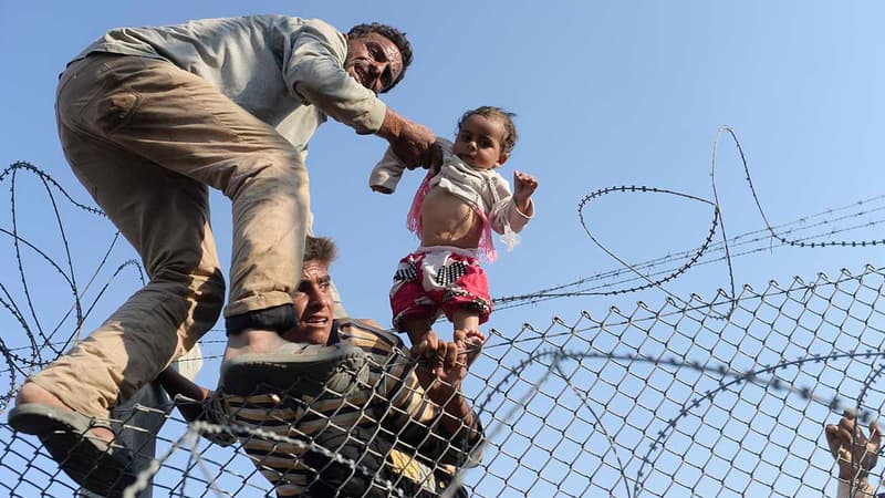 Une photo de Bulent Kilic, photographe de l'AFP primé au Visa pour l'image 2015, montrant un enfant syrien porté au dessus de la frontière.