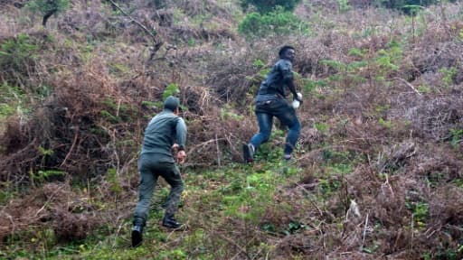 Un membre des forces marocaines poursuit un migrant qui vient de forcer la barrière de l'enclave de Ceuta le 18 février 2017 à Fnideq au Maroc