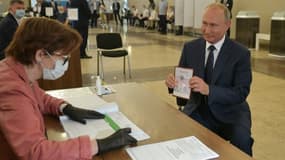 Le président de la Russie, Vladimir Poutine, montre son passeport à une membre d'une commission électorale pour participer au scrutin dans un bureau de vote de Moscou, le 1er juillet 2020