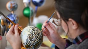 Une femme en train de peindre une décoration de Noël (illustration)