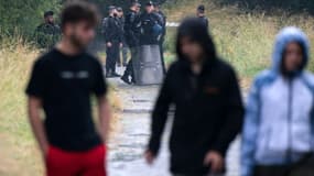 Des teufeurs passent devant les forces de l'ordre dans un champ près du lieu de la rave-party illégale organisée à Redon, en Ille-et-Vilaine, le 19 juin 2021