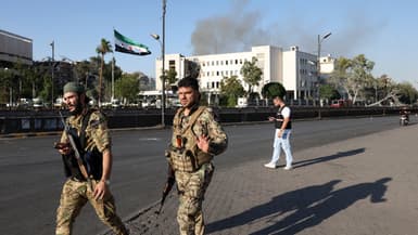 Les forces de sécurité syriennes montent la garde devant le complexe du siège de l'armée syrienne et du ministère de la Défense, gravement endommagé, à Damas, après les frappes israéliennes du 16 juillet 2025.