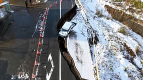 Une photo prise par un drone montre une voiture tombée dans une route effondrée à la suite d'un violent séisme à Tohoku, dans la préfecture d'Aomori, au Japon, le 9 décembre 2025.