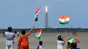 Des personnes agitent des drapeaux indiens alors qu'une fusée de l'Organisation indienne de recherche spatiale (ISRO) transportant le vaisseau spatial Chandrayaan-3 décolle du Centre spatial Satish Dhawan, dans l'État de l'Andhra Pradesh (sud du pays), le 14 juillet 2023.