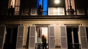 Des Parisiens en train d'applaudir les soignants depuis les fenêtres de chez eux.