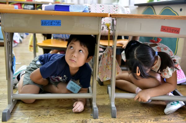 Des écoliers de Tokyo s'abritent sous les tables pendant un exerce antisismique, le 1er septembre 2023