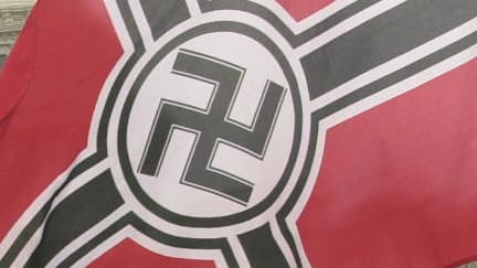 ILLUSTRATION - Un membre de la "Neo-Nazi National Alliance" brandit un drapeau néonazi lors d'une manifestation contre le soutien des Etats-Unis à Israël, à Washington le 24 août 2002.