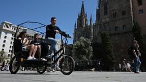 Les touristes profitent d'une balade en vélo-taxi sur la Plaza de la Catedral à Barcelone, le 11 mai 2022. 