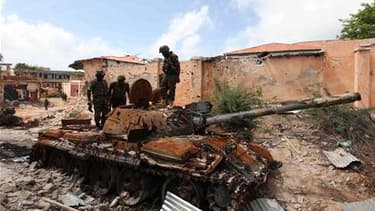Soldats de la force de paix de l'Union africaine inspectant un de leurs chars détruit par les milices Chabaab à Mogadiscio. Les combats ont repris dimanche dans la capitale somalienne au lendemain de l'annonce par les rebelles qu'ils abandonnaient la vill