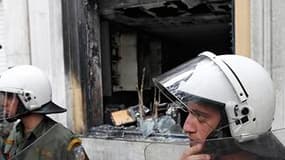 Policiers devant un immeuble abritant une agence bancaire à Athènes, qui a pris feu après avoir été la cible de cocktails Molotov, mercredi. Trois personnes ont péri dans cet incendie en marge des manifestations contre le plan d'austérité négocié par le g