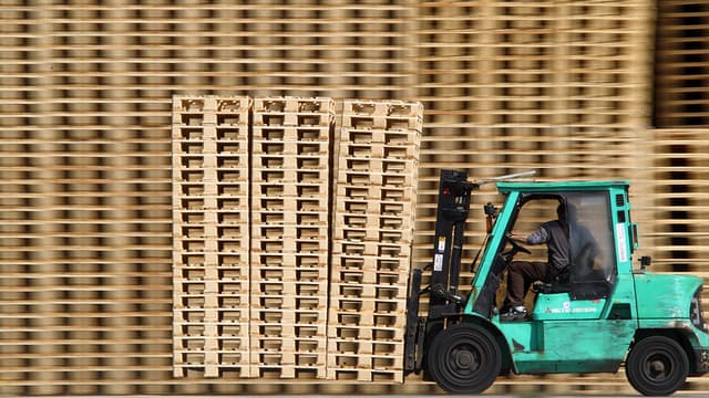 Un salarié déplace des palettes en bois (photo d'illustration).