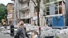 Des personnes passent devant un immeuble résidentiel détruit à la suite d'une attaque de drone à Kiev le 25 mai 2025